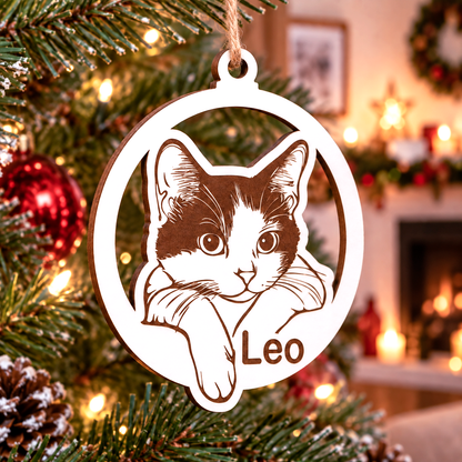 Simulación: bola navideña blanca con retrato de un gato y el nombre Leo, colgada con cuerda marrón.